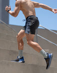 Flow shorts in blue and black worn by a man running up stairs, showcasing style and performance for workouts.