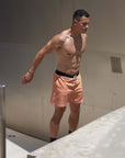 Model wearing Flow shorts in Desert Orange, showcasing moisture-wicking and quick-drying features for hot yoga.
