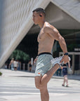 Man stretching outdoors in Flow shorts - Lichen, showcasing flexibility and style.