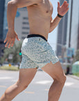 Man running in Flow shorts - Lichen, showcasing flexibility and style in an urban setting.