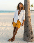 Flow shorts in saffron color, perfect for hot yoga and beach wear, paired with a white shirt and casual sandals.