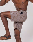 Man demonstrating movement in 4-way stretch Swerve Shorts in Smoky Quartz color with a side pocket.