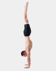 Man performing a handstand in 4-way stretch Swerve Shorts - Crow Black for optimal movement and flexibility.
