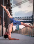 Man performing an acrobatic move in 4-way stretch Swerve Shorts, showcasing flexibility and movement support.